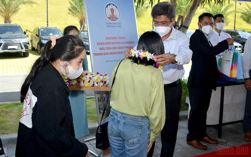 Phó Chủ tịch UBND tỉnh Bình Thuận Nguyễn Minh trao hoa chào mừng những du khách đầu tiên đến Bình Thuận trong trạng thái bình thường mới.