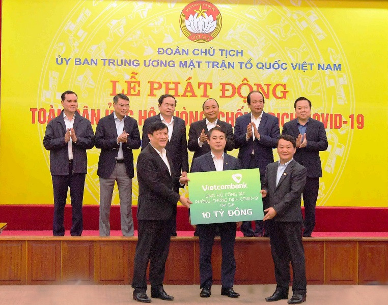 Đồng chí Nghiêm Xuân Thành - Chủ tịch HĐQT Vietcombank (giữa) trao biển tượng trưng số tiền ủng hộ công tác phòng, chống dịch Covid-19 của Vietcombank tại Lễ phát động toàn dân ủng hộ phòng, chống dịch Covid-19 do Ủy ban Trung ương MTTQ Việt Nam phát động với sự chứng kiến của Thủ tướng Chính phủ và lãnh đạo các bộ, ban, ngành.