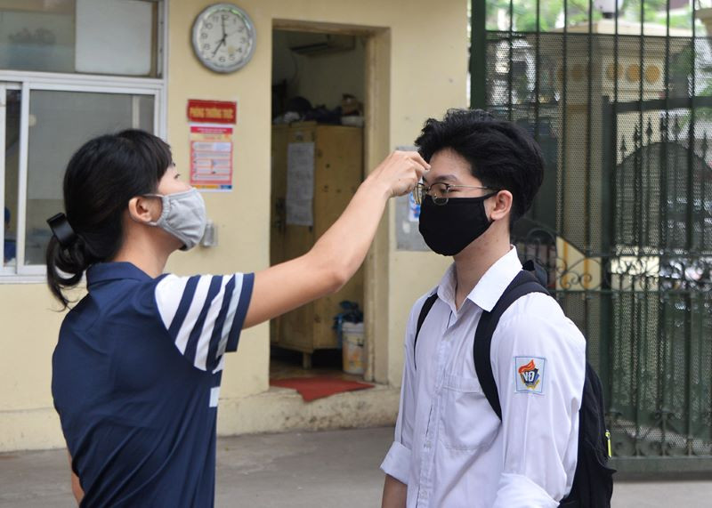 Đo thân nhiệt cho học sinh trước khi vào trường (Ảnh: THỦY NGUYÊN)