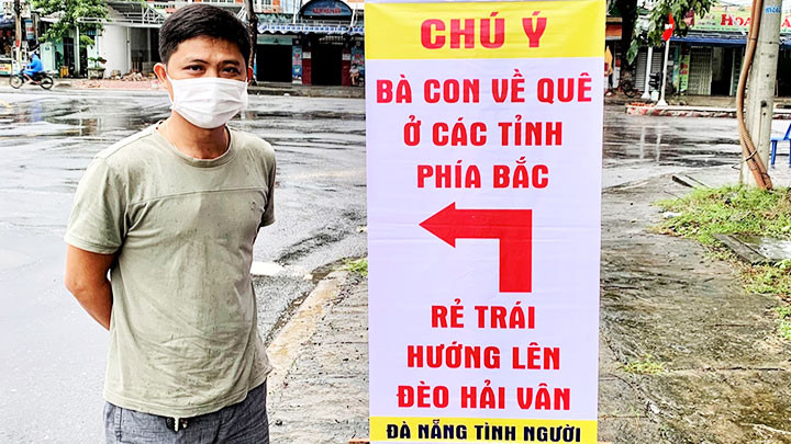Anh Đặng bên tấm bảng chỉ đường để người dân về quê không bị lạc.