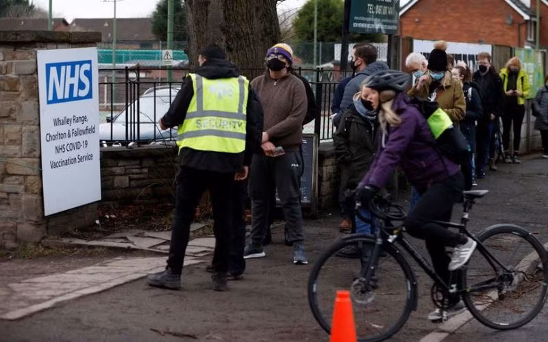 Xếp hàng chờ tiêm vaccine phòng Covid-19 liều tăng cường bên ngoài 1 trung tâm tiêm chủng ở Manchester, Anh, ngày 13/12/2021. (Ảnh: Reuters)
