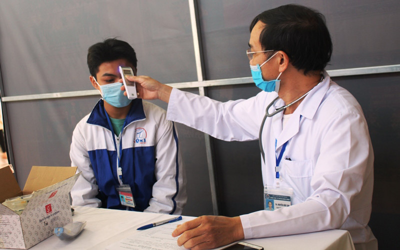 Nhân viên y tế thăm, khám sức khỏe, kiểm tra thân nhiệt học sinh trước khi tiêm.