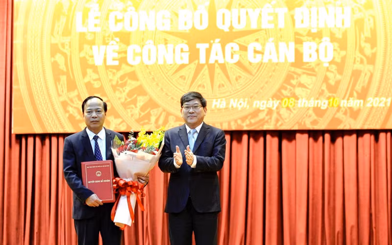 PGS, TS Nguyễn Duy Bắc, Phó Bí thư Đảng ủy, Phó Giám đốc Học viện Chính trị quốc gia Hồ Chí Minh trao quyết định và tặng hoa chúc mừng PGS, TS Mai Đức Ngọc.