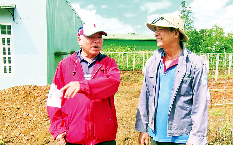 Linh mục Dương Công Hồ (trái) trao đổi với người dân về việc hỗ trợ mở rộng đường dân sinh khu vực giáo xứ.