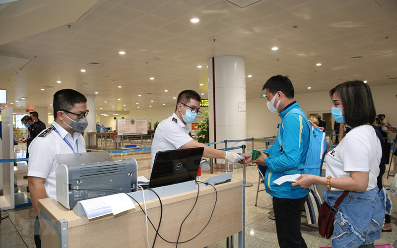 Nhân viên y tế kiểm tra phiếu khai báo y tế của hành khách trước khi làm thủ tục nhập cảnh tại cửa khẩu Sân bay quốc tế Nội Bài (Ảnh: TTXVN)