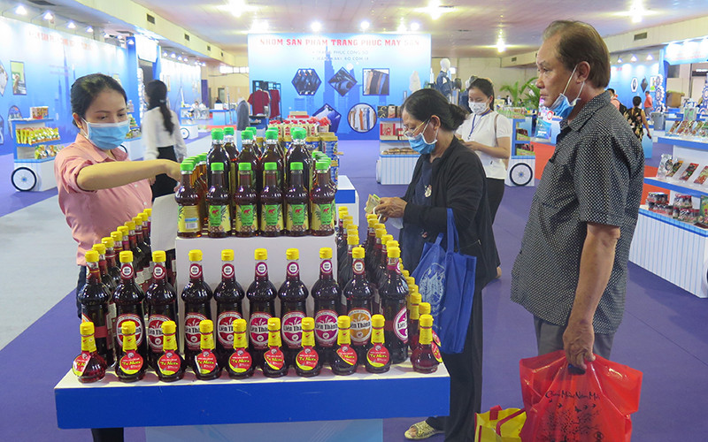 Người dân tham quan, mua sắm hàng hóa tại một gian hàng ở Hội chợ – Triển lãm trong tối ngày 29-7.