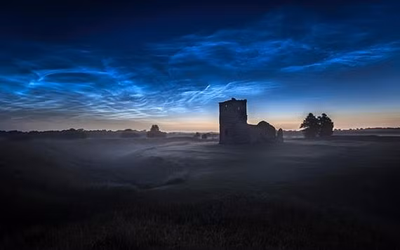 Những đám mây dạ quang được chụp trên Nhà thờ Knowlton ở Dorset, Vương quốc Anh, bởi nhà thiên văn học Ollie Taylor vào rạng sáng ngày 22-6. Ảnh: Ollie Taylor.