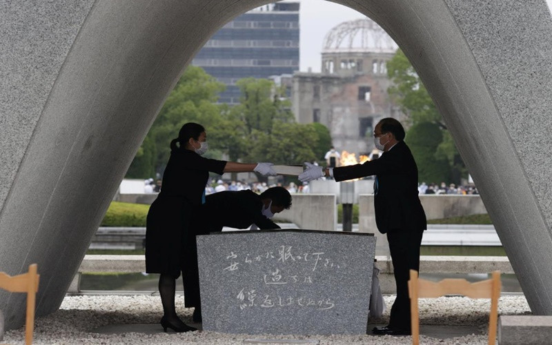 Thị trưởng Matsui Kazumi chuẩn bị đặt danh sách nạn nhân của vụ ném bom vào bên trong bia tưởng niệm. (Ảnh: Kyodo News)
