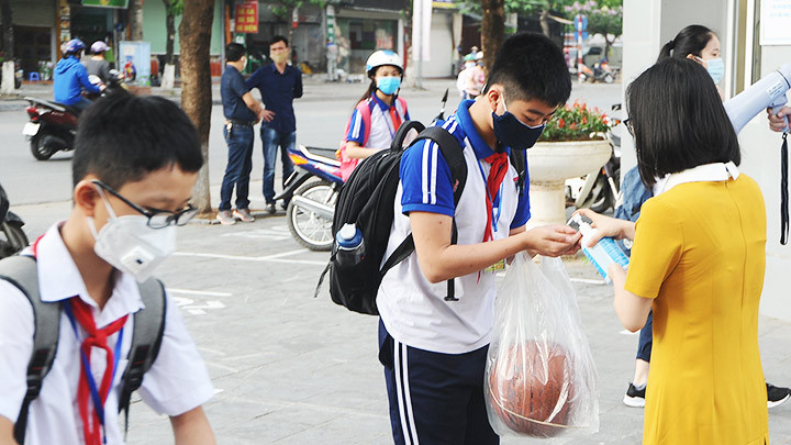 Học sinh sát khuẩn và kiểm tra thân nhiệt trước khi vào lớp học. Ảnh: SONG ANH