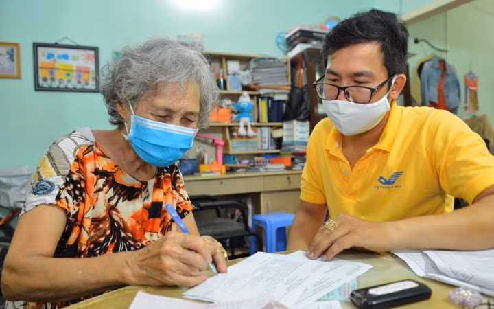 Người dân phấn khởi khi được nhận lương hưu tại nhà ở (phường Tân Định, quận 1, TP Hồ Chí Minh) trong đợt phòng, chống dịch Covid-19 vừa qua.