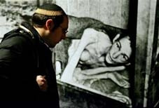 Một người Do Thái đang xem <br> ảnh nạn nhân sống sót <br> sau vụ tàn sát ở trại Auschwitz.