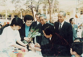 Giáo sư Đặng Đức Trạch
(người đứng ngoài, bên phải)
kiểm tra hoạt động cho trẻ em
uống vaccine phòng bệnh.