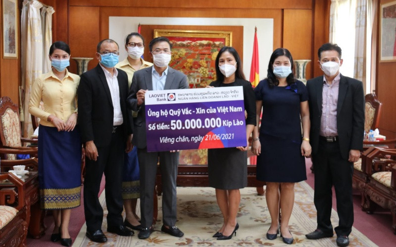 Tổng Giám đốc LaoVietBank Nguyễn Đức Vũ (trái) trao 50 triệu kíp Lào đóng góp vào Quỹ Vaccine phòng Covid-19, chiều 21-6.
