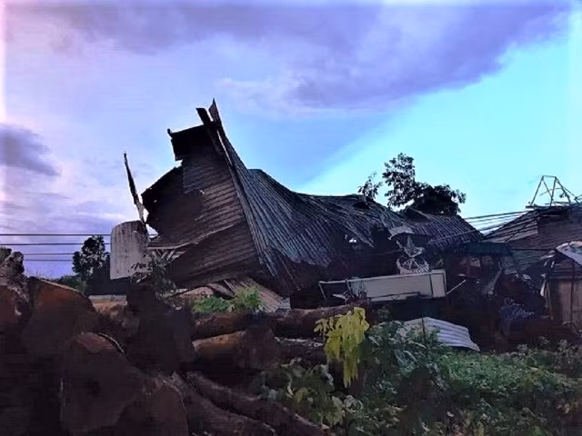 Gió lốc cuốn mái tôn nhà dân trùm lên đường dây điện.