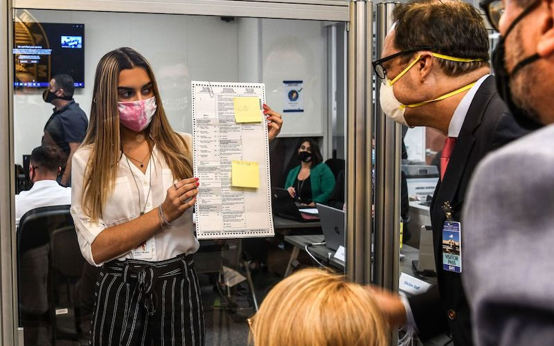 Các nhân viên bầu cử kiểm tra một lá phiếu được bầu qua đường bưu điện tại Miami, ngày 3-11-2020. (Ảnh: Getty Images)