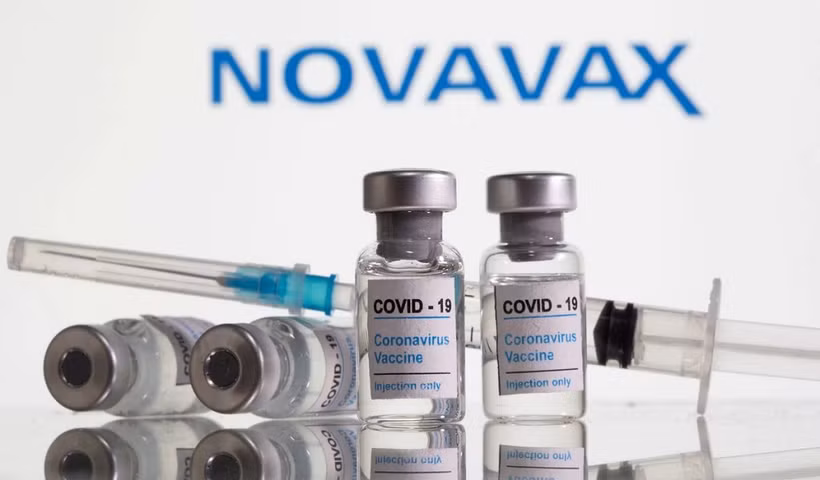 Các lọ dán nhãn vaccine ngừa Covid-19 và ống tiêm được nhìn thấy phía trước logo Novavax. (Ảnh: Reuters).