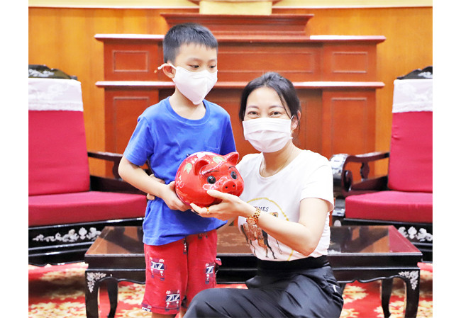 Bé Phan Anh Khôi ủng hộ tiền tiết kiệm trong lợn đất cho Quỹ phòng, chống dịch Covid-19.