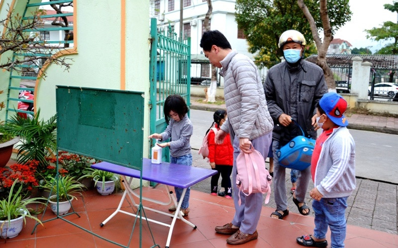 Học sinh Trường mầm non Hoa Đào thực hiện sát khuẩn tay và đeo khẩu trang trước khi vào lớp học.