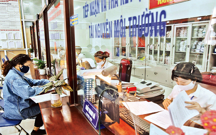 Cán bộ Bộ phận một cửa UBND quận Bắc Từ Liêm giải quyết thủ tục hành chính cho người dân. Ảnh: ANH VŨ