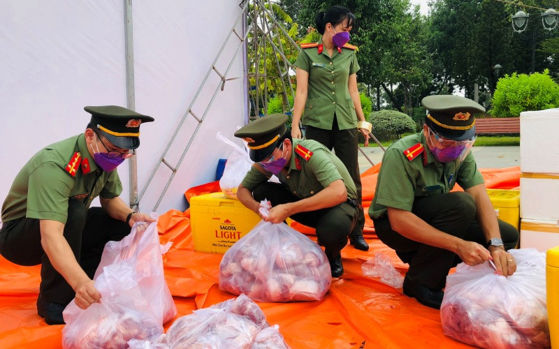 Chiến sĩ Công an tỉnh Đồng Nai chia thịt heo ra từng gói nhỏ trước khi đưa đi trao tặng người dân.