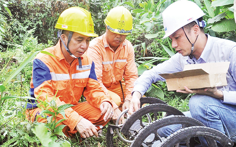 Hoàng Văn Thiện (bên trái) cùng anh em kéo điện qua núi.