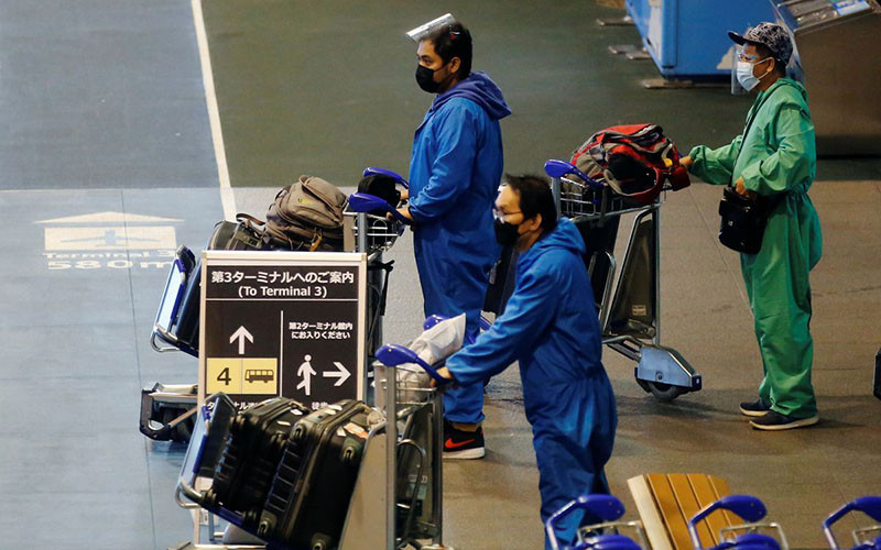 Hành khách mặc đồ bảo hộ di chuyển tới điểm chờ xe buýt tại sân bay quốc tế Narita, Nhật Bản, ngày 30/11. (Ảnh: Reuters)