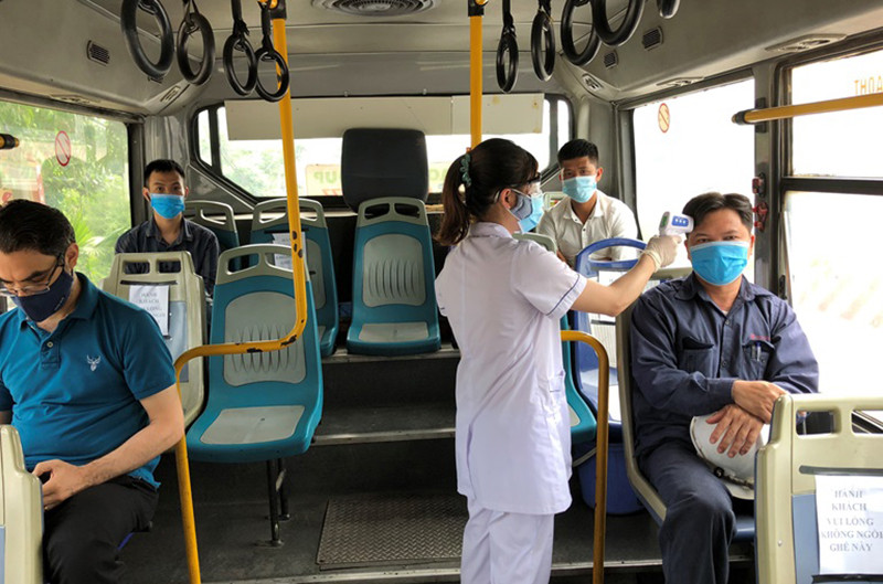 Nhân viên y tế đo thân nhiệt trên xe buýt đưa, đón công nhân miễn phí.