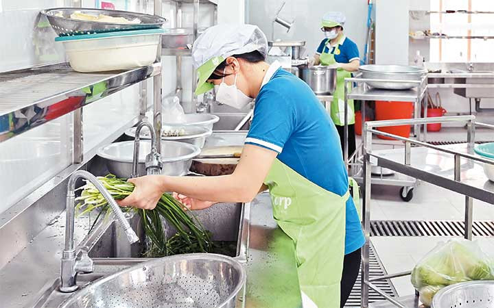 Nhân viên Trường mầm non Hoa Hướng Dương, quận Cầu Giấy chuẩn bị bữa ăn bán trú cho học sinh. (Ảnh Thu Hà)