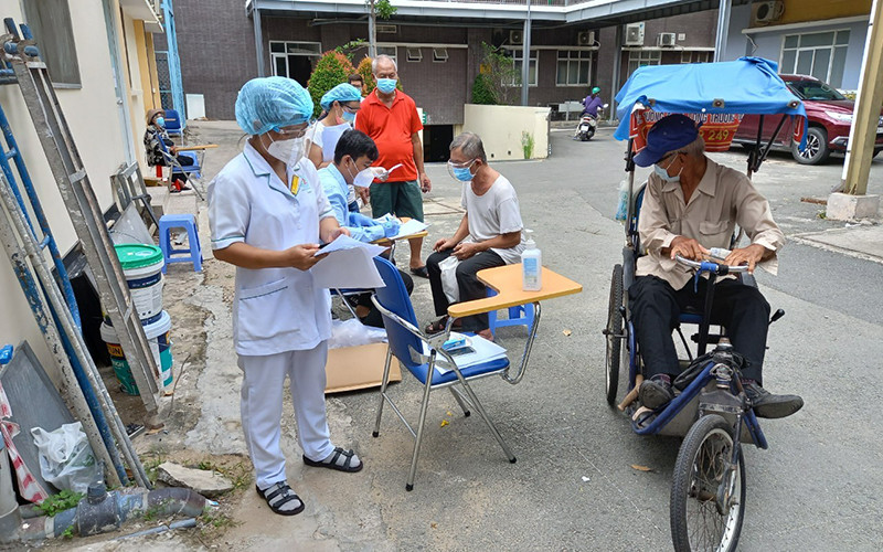 Nhân viên y tế kiểm tra kỹ thông tin trước bên ngoài phòng tiêm chủng.