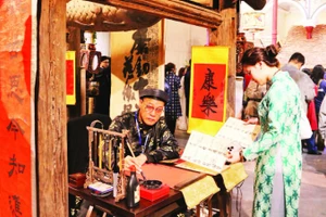 Du khách thích thú với hình ảnh ông đồ bên mực tàu, giấy đỏ trong phố cổ.