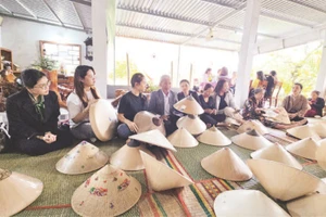 Du khách tìm hiểu các công đoạn chế tác nón ngựa tại cơ sở của Nghệ nhân Ưu tú Đỗ Văn Lan.