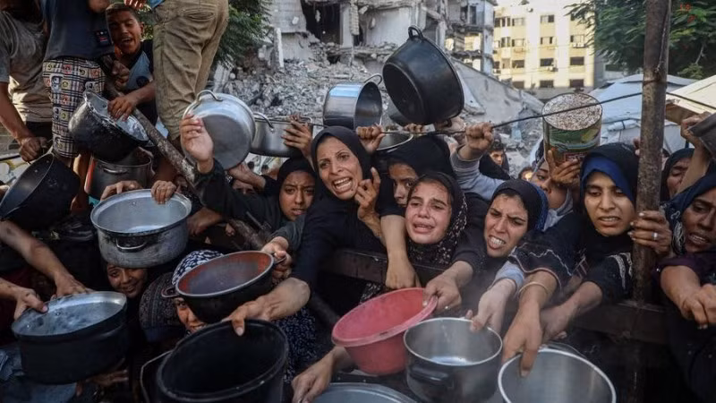 Người dân Palestine di dời khỏi chiến sự chờ nhận thực phẩm miễn phí từ một trung tâm phân phối thực phẩm ở thành phố Gaza, ngày 14/7/2025. (Ảnh: Xinhua)