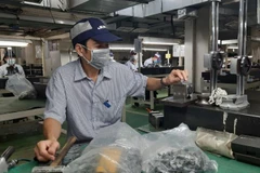 Công nhân Công ty trách nhiệm hữu hạn Juki Việt Nam, Khu Chế xuất Tân Thuận, Thành phố Hồ Chí Minh đang sản xuất các linh kiện máy may công nghiệp.