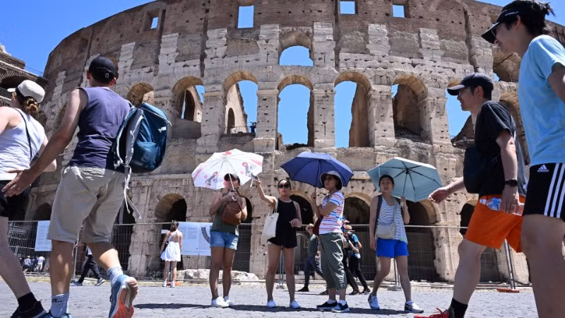 Khách du lịch che ô tránh nắng nóng khi tham quan Đấu trường La Mã ở Rome, Italia ngày 12/7/2024. (Ảnh: THX/TTXVN)