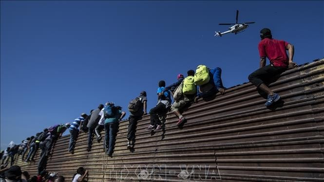 Người di cư trèo qua bức tường biên giới Mexico-Mỹ, gần cửa khẩu El Chaparral ở Tijuana, bang Baja California, Mexico. (Ảnh tư liệu: TTXVN)