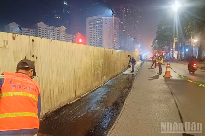 Công nhân thảm lại mặt đường sau khi dỡ bỏ phần quây tôn để trả lại mặt đường cho người tham gia giao thông.