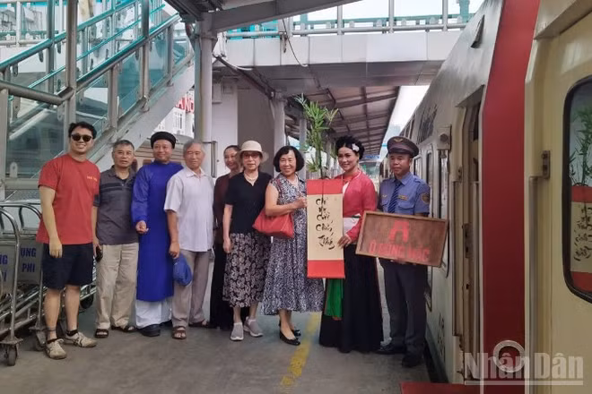 Du khách đi tàu di sản "tàu Hà Nội 5 cửa Ô" chụp ảnh lưu niệm cùng nhân viên phục vụ tàu.