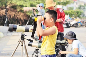 Các em nhỏ trải nghiệm ống nhòm chuyên dụng.