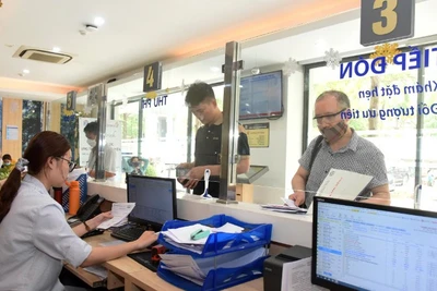 Nhân viên Bệnh viện Ung bướu Hà Nội hướng dẫn bệnh nhân làm các thủ tục khám, chữa bệnh bảo hiểm y tế. (Ảnh: KHÁNH AN)