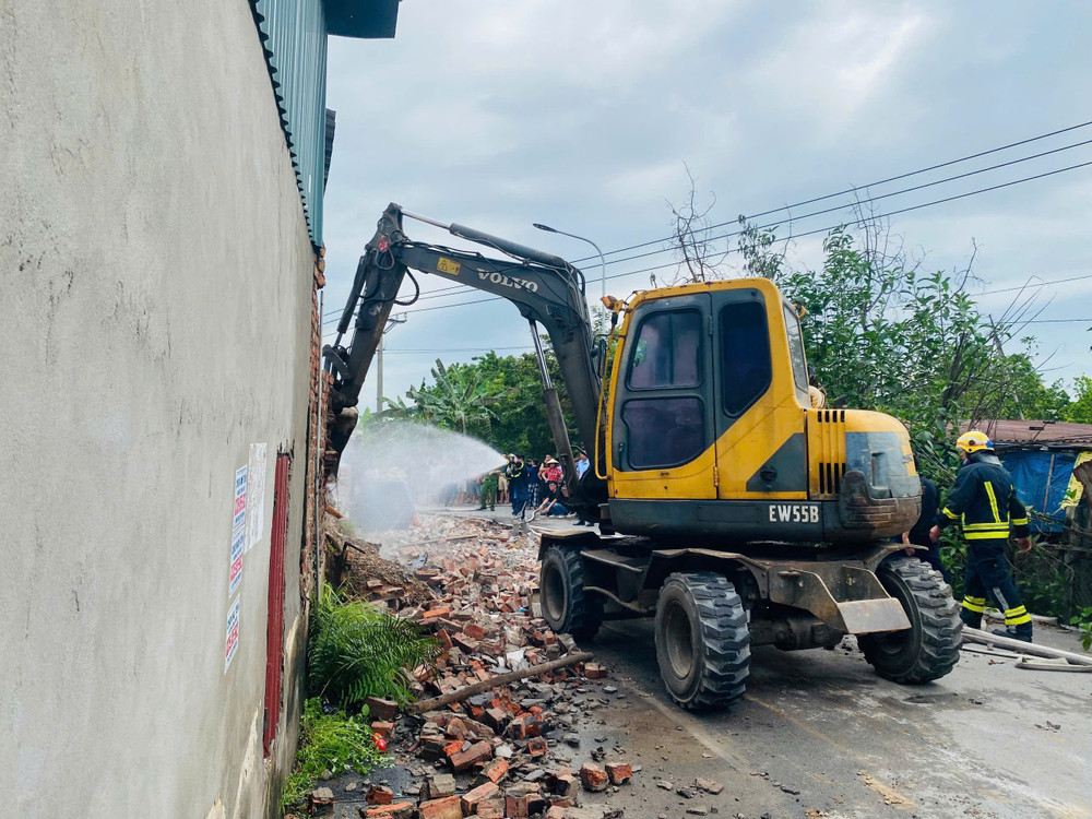 Lực lượng chức năng dùng máy xúc phá tường để khống chế đám cháy. z6667369811036-de65e21e6983ddcd33697f6d935cbec5.jpg