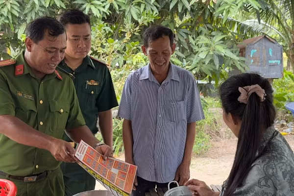Trung tá Châu Văn Nát phát tờ rơi tuyên truyền cho người dân các phương thức tội phạm mới để nâng cao cảnh giác.