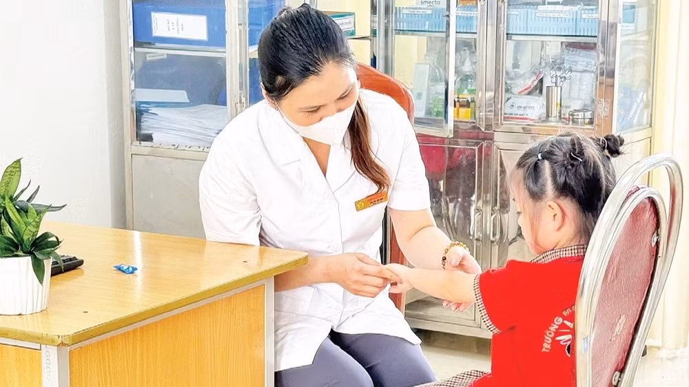 Cán bộ y tế kiểm tra, theo dõi trẻ mắc bệnh tay chân miệng trên địa bàn thành phố Hà Nội.