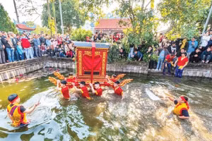 Trai tráng làng Thọ Lộc rước kiệu dưới nước, trước sự cổ vũ của người dân.