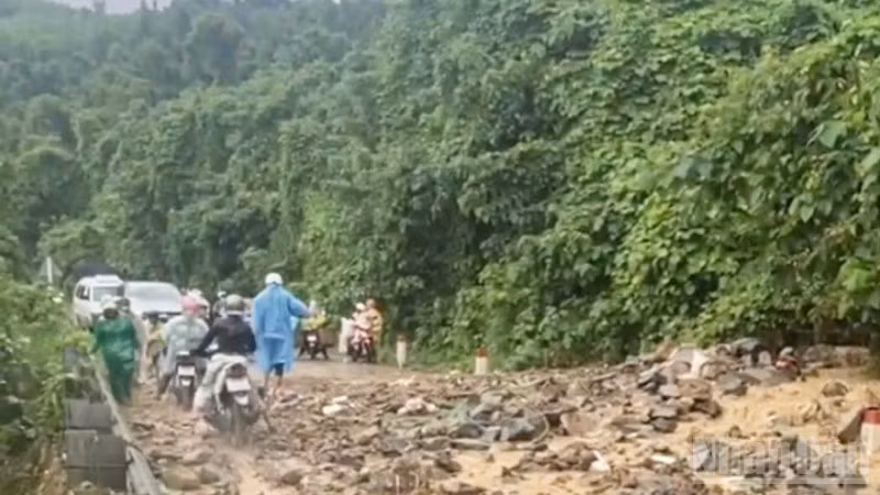 Nước mưa đã cuốn phăng đất, đá từ ta-luy trên cao tràn xuống mặt đường, gây mất an toàn giao thông, cản trở việc đi lại của người dân. (Ảnh: VŨ TÂN)