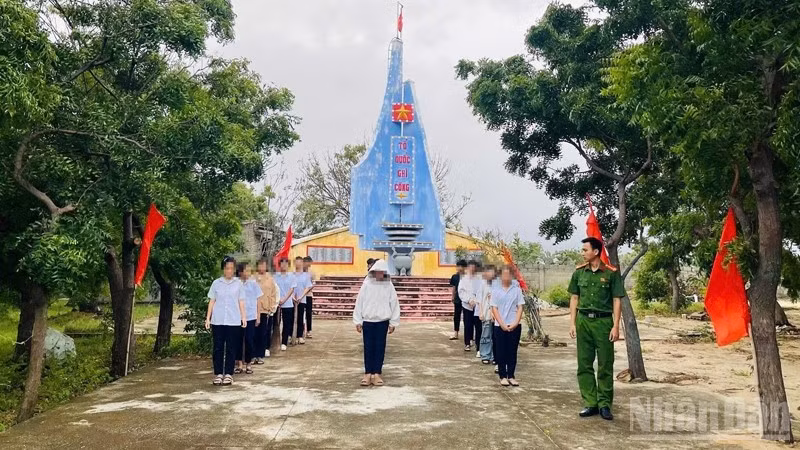 Thanh thiếu niên có hành vi vi phạm tập trung tại khuôn viên Đài tưởng niệm Liệt sĩ xã Phước Dinh để nghe Công an xã tuyên truyền, giáo dục pháp luật và tham gia lao động công ích có sự giám sát của công an xã. (Ảnh: NGUYỄN TRUNG)
