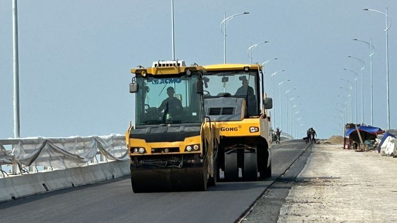 Thi công trải thảm bê-tông nhựa trên cây cầu vượt sông Hồng thuộc dự án đường bộ ven biển tỉnh Hưng Yên.