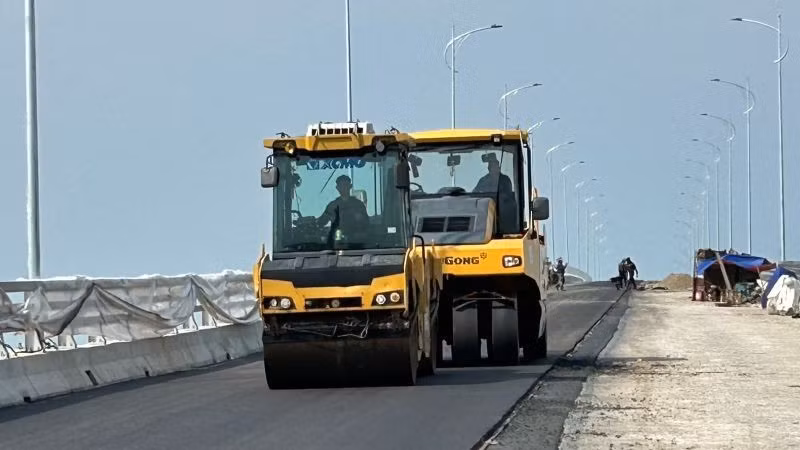 Thi công trải thảm bê-tông nhựa trên cây cầu vượt sông Hồng thuộc dự án đường bộ ven biển tỉnh Hưng Yên.