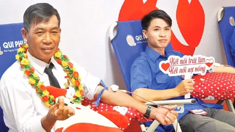 Ông Trần Minh Mến (bên trái) tham gia hiến máu tình nguyện. (Ảnh: Lê Minh)