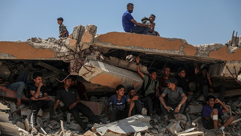 Người dân Palestine ngồi trên đống đổ nát ở khu vực Sudaniya, phía bắc thành phố Gaza. (Ảnh: Tân Hoa Xã/TTXVN) 