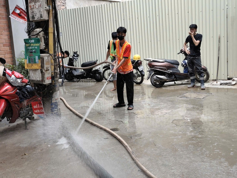Công nhân tiến hành dọn rửa vệ sinh bùn đất tại ngõ 7 Giang Văn Minh bằng vòi nước chuyên dụng. (Ảnh: VĂN THỊNH) z6992582815440-e4c12fb14304b95b59a95e9b54b413cf.jpg